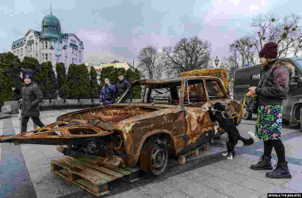 Люди смотрят на сожженные автомобили, которые волонтеры привезли с линии фронта под Бахмутом, чтобы показать последствия войны и собрать средства на новые автомобили для украинских военных, Львов, Украина.