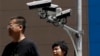 China US Trade - People walk by Chinese-made surveillance cameras installed along a street in Beijing, Thursday, May 23, 2019. The Chinese video surveillance company Hikvision says it is taking concern about the use of its technology seriously following a