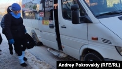 Женщина старается не упасть при посадке в маршрутку