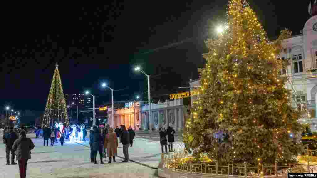 Евпатория.&nbsp;В этом году на Театральной площади установили искусственную главную городскую елку высотой 11 метров. Прежде такой роли удостаивалась живая, растущая, которую тоже украсили (справа).