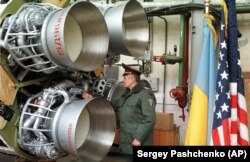 Український офіцер оглядає ракету УР-100Н перед її демонтажем. Дніпро, 26 лютого 1999 року. Ракету було знищено в рамках відмови України від ядерної зброї, що було обумовлено Будапештським меморандумом, підписаним у 1994 році. Згідно із цим Меморандумом США, Росія і Велика Британія зобов'язалися поважати незалежність, суверенітет та існуючі кордони України