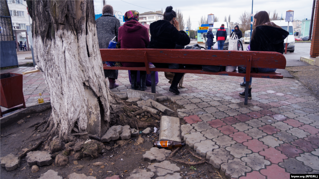 Пассажиры на скамейке у здания автостанции, что на той же улице, рядом с железнодорожным вокзалом