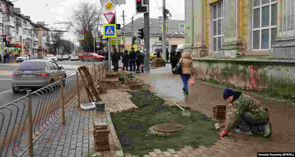 Рабочий за укладкой тротуарной плитки возле храма святых равноапостольных князя Владимира и Ольги Киевского патриархата